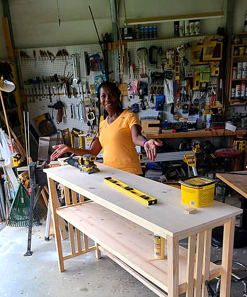 A pine console table on the bench in the Grace Woodwork shop, tools on the pegboard behind